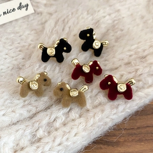 Flocked puppy stud earrings in black, brown, and red on a white knit background