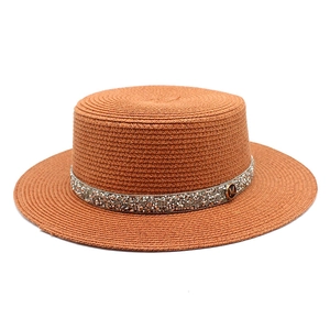 Brown straw boater hat with shimmering rhinestone band and M-logo metal badge