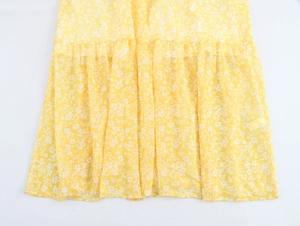 Detail view of floral maxi dress hem featuring pleated ruffles and soft yellow fabric