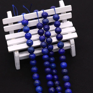 Deep blue lapis lazuli round beads on a white miniature stool with black background