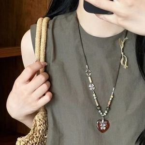 Ethnic style beaded necklace with heart pendant and woven cord on a female model