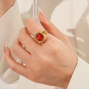 Dettaglio di un anello vintage dorato con una grande pietra rossa tonda sfaccettata