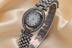 Vista macro di un orologio al quarzo nero con strass brillanti su tessuto di raso