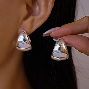Close-up of chunky silver water drop earrings with a high-polished mirror finish