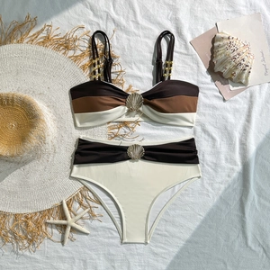 Detailed flat lay of color-blocked bikini featuring shell charms and beach accessories