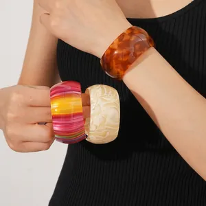 Three wide acetate open bangles in tortoiseshell, rainbow, and marble patterns on a model