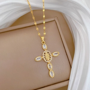 Detail of a gold cross pendant with cubic zirconia on a luxury beige jewelry box