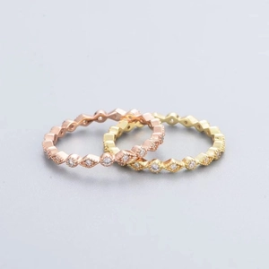 Dettaglio di anelli eternity in oro rosa e oro con motivo geometrico a rombi diamantati