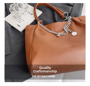 Close-up of brown litchi pattern leather tote with silver metal chain and pendant details