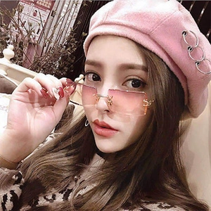 Detail of pink gradient rimless sunglasses and beret with silver rings on female model
