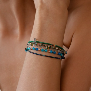 Detailopname van een bohemian gelaagde kralenarmband met groene en gouden kralen om de pols