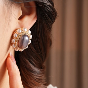 Close-up of vintage gold zircon earrings with grey-purple oval stone and pearls