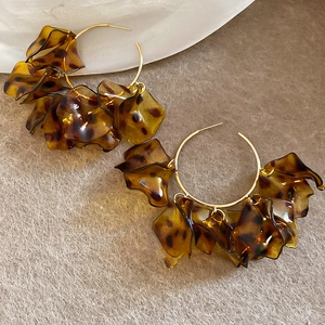 Macro detail of amber leopard print petal earrings with gold-toned C-shape metal finish