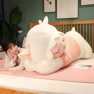 Close-up of a large plush sheep pillow wearing a pink ribbed knit sweater on a cozy bed