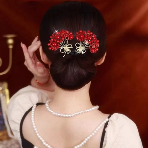 Détail de pinces à cheveux baies rouges et feuilles dorées sur un chignon élégant