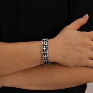 Close-up of men's stainless steel cross bracelet on wrist with black silicone band