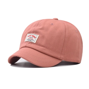 Detailed shot of coral pink cotton baseball cap with short brim and retro embroidery patch
