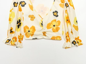 Close-up of V-neck floral print top with puffed ruffle sleeves and ribbed knit texture
