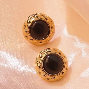 Detailed view of vintage gold round stud earrings with quilted texture and dark cat eye stone