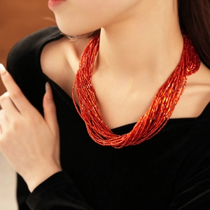 Dettaglio della collana di perle rosse multistrato su un abito di velluto nero
