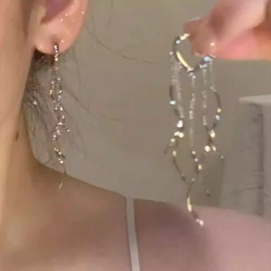 Close-up of silver tassel earrings with wavy fringe and sparkling rhinestone details