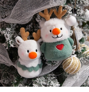 Close-up of white plush reindeer Christmas ornaments hanging on a decorated festive tree