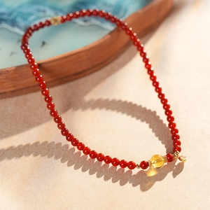 Détail d'un bracelet en perles d'agate rouge avec gemme jaune et pendentif coeur