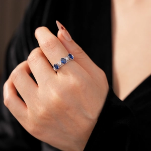 Détail d'une bague dentelle argentée avec trois gemmes bleues ovales et petits diamants