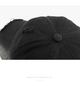 Detail of distressed vintage black cotton baseball cap showing ripped fabric texture