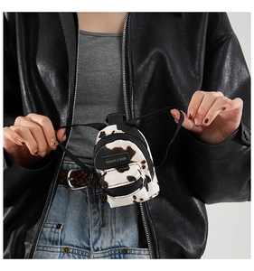 Miniature cow print backpack accessory featuring a zip pocket and Fashion & Bags tag