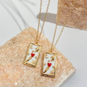 Gold plated tarot necklace The Lovers pendant on beige stone background in a 45-degree angle