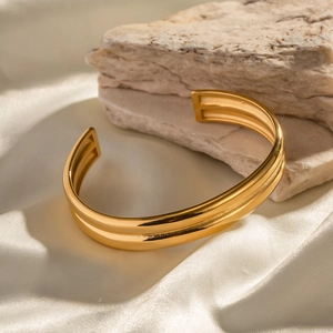 Bracciale rigido a doppio strato in acciaio placcato oro 18k su fondo in raso