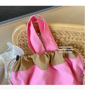 Dettaglio della borsa a secchiello in nylon rosa con coulisse marrone e manico robusto