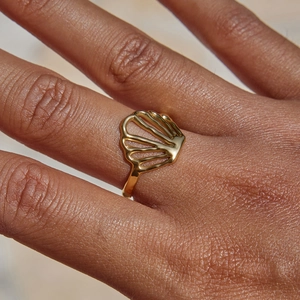 Macro shot of gold shell hollow ring on finger showcasing oceanic design details