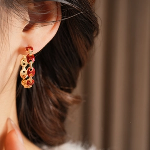 Detail of 18k gold plated pig nose earrings with red enamel and zircon on a model