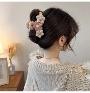 Detail view of woven pink and beige knit flower hair claw clip worn on hair