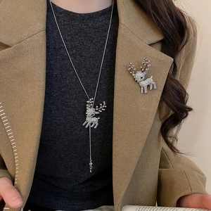 Close-up of sparkling rhinestone reindeer brooch and necklace set on a camel coat