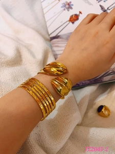 Detail of multi-layer gold titanium steel bangles and leaf ring on a female model