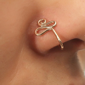Macro shot of gold spiral non-piercing nose cuff with intricate curved metal design