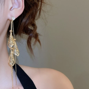 Close-up of golden fringe earrings featuring heart studs and tiered hollow cones