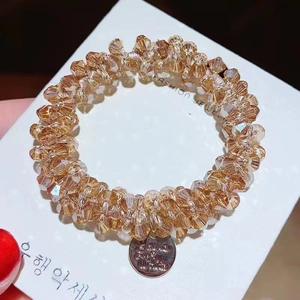 Close-up of faceted champagne crystal beads on an elastic hair tie with silver pendant
