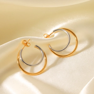 Detail of two-tone double hoop earrings in gold and silver finish on silk background