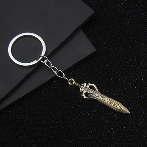 Vintage bronze miniature sword keychain with intricate embossed patterns on a dark background