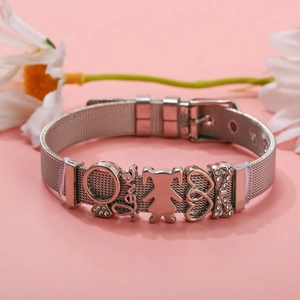 Macro shot of silver mesh bracelet with Love, heart, and girl charms on pink background