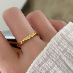 Detail of gold irregular ring with Je t'aime engraving shown on a finger