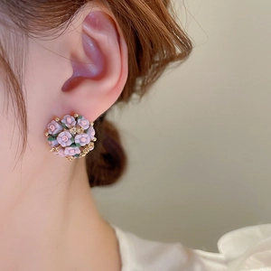 Detailed close-up of a pink floral cluster stud earring with gold beads and rhinestones