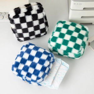 Trousses de maquillage à damier en peluche noires, bleues et vertes sur bureau blanc