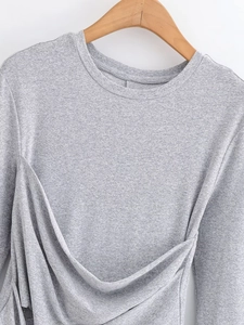 Detailed close-up of grey long sleeve top with unique layered ruffles on a wooden hanger