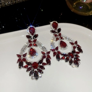 Macro detail of vintage silver-needle square earrings with red and clear rhinestones