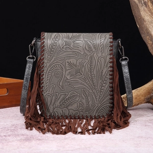 Detail of vintage bohemian crossbody bag with floral embossing and long leather tassels